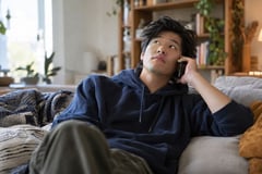 Man on a couch waiting on a call with his phone